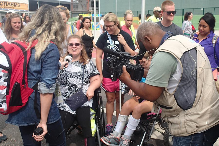 Two journalism students interviewing a group of fans who were gathered outside the Rio Paralympic games on 足彩平台’s first Diversity in Sports travel study.