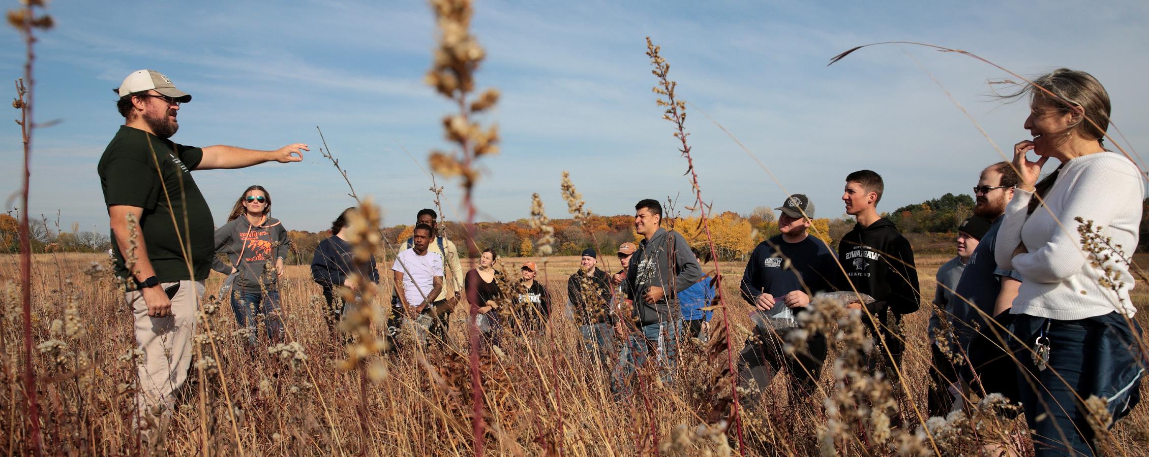 A class meets in the prairie to harvest seeds.