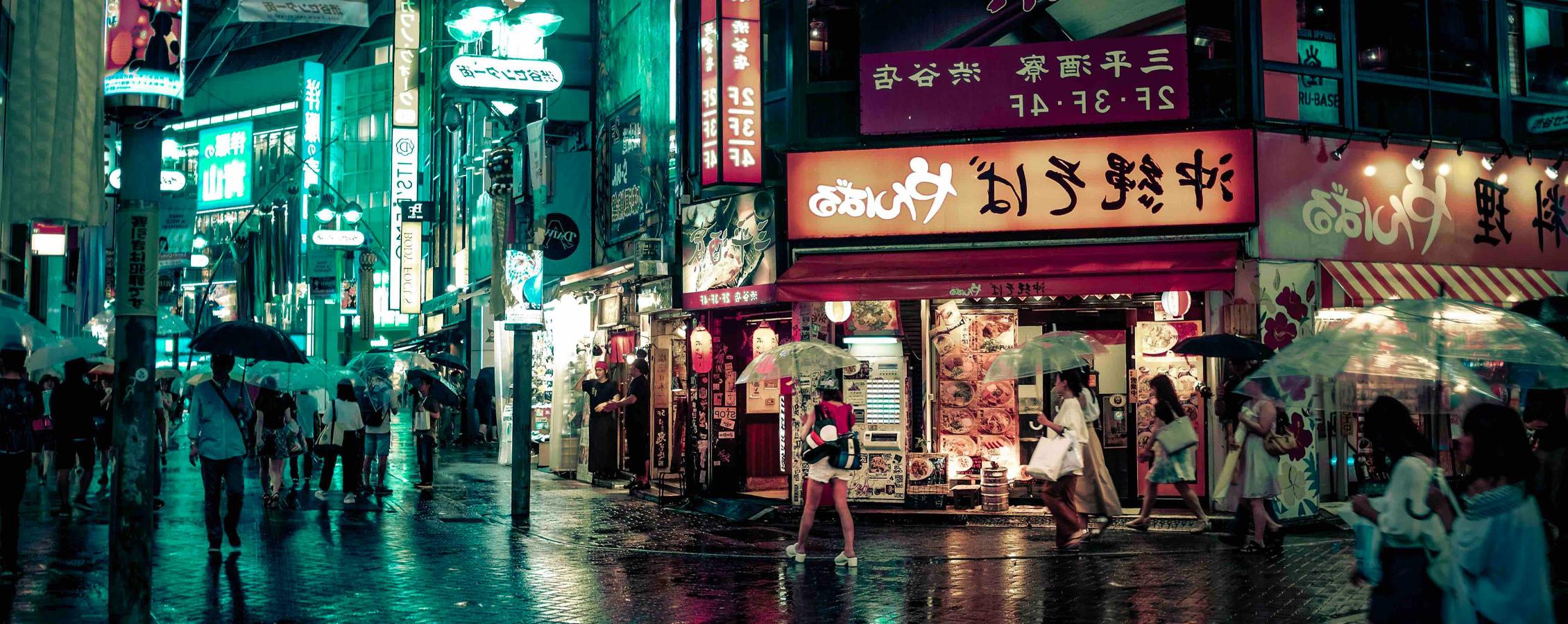 Street lights glow in a busy, urban city in Japan at night.