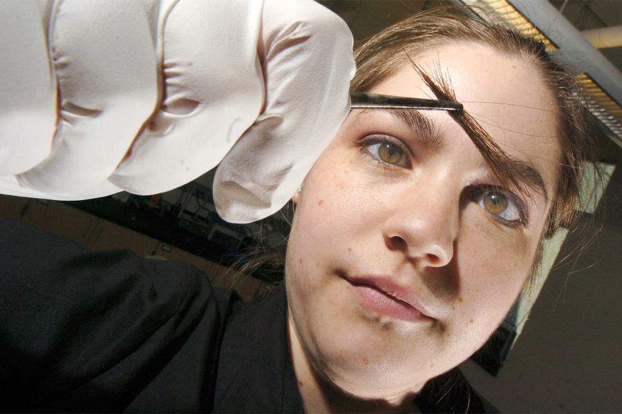 A student inspects hair in a tweezers.