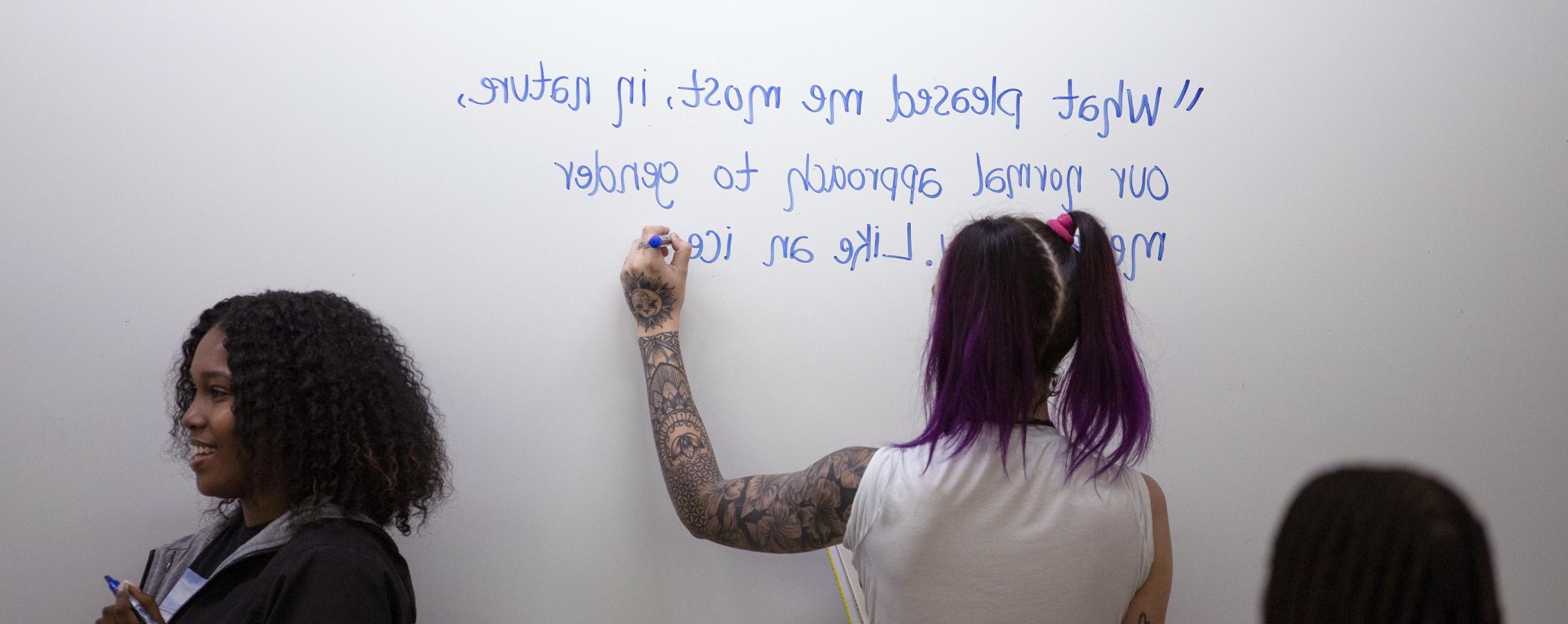 A person writes a quote on a whiteboard.