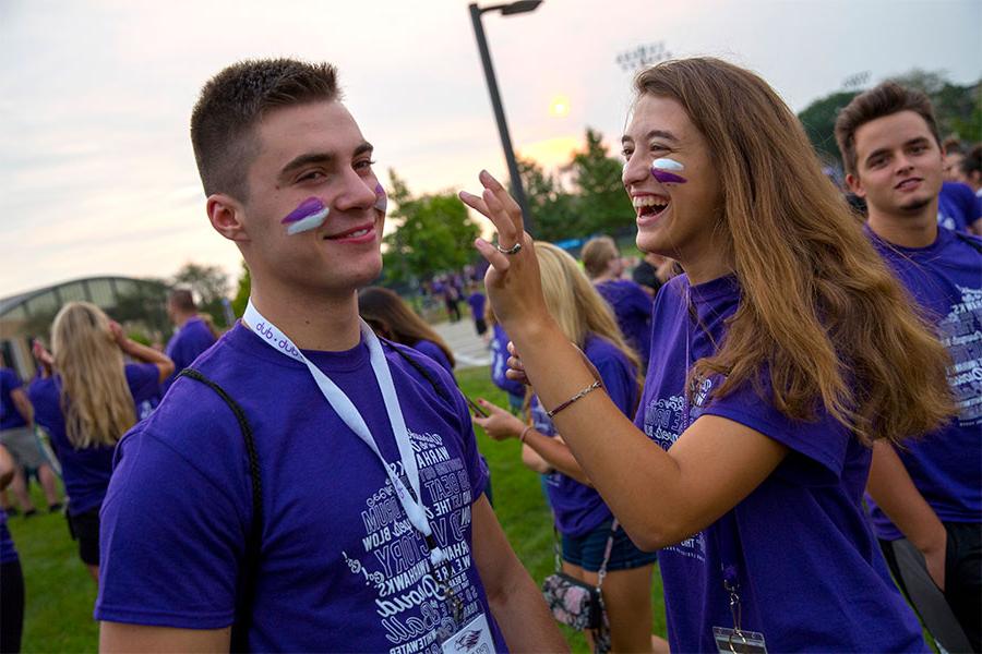 Students apply face paint during a welcome rally.