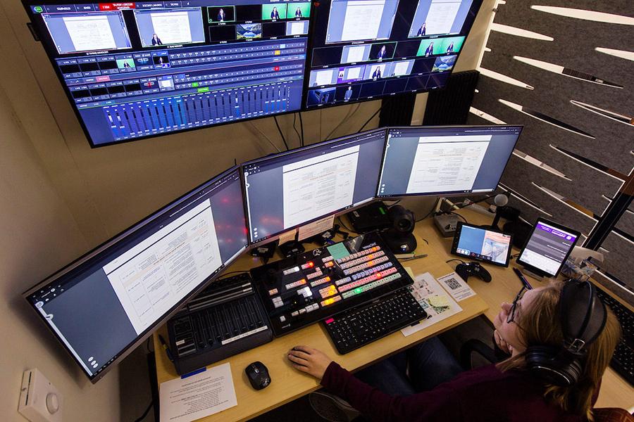 A student looking at three monitors doing work