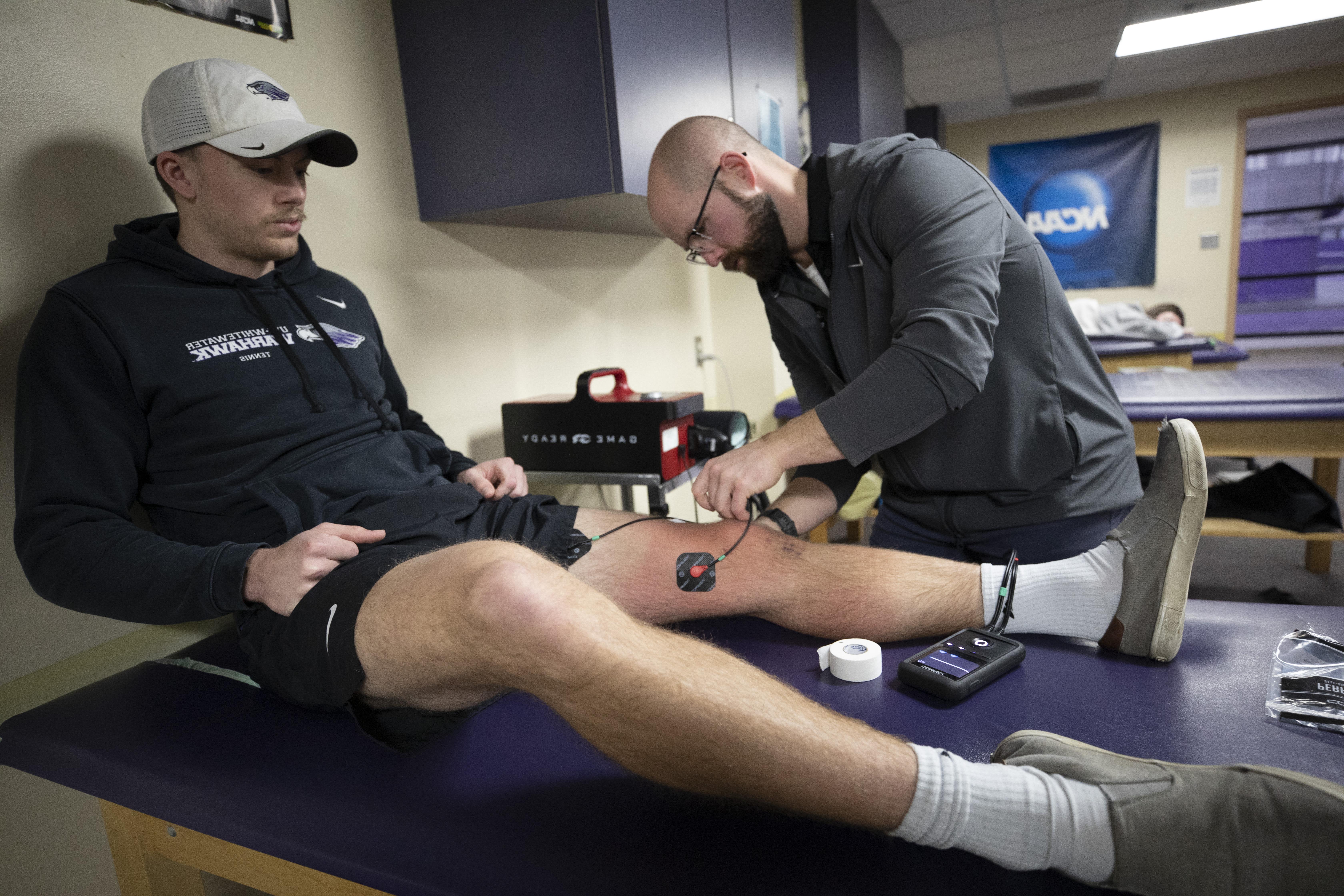 Trainer putting electrodes on leg