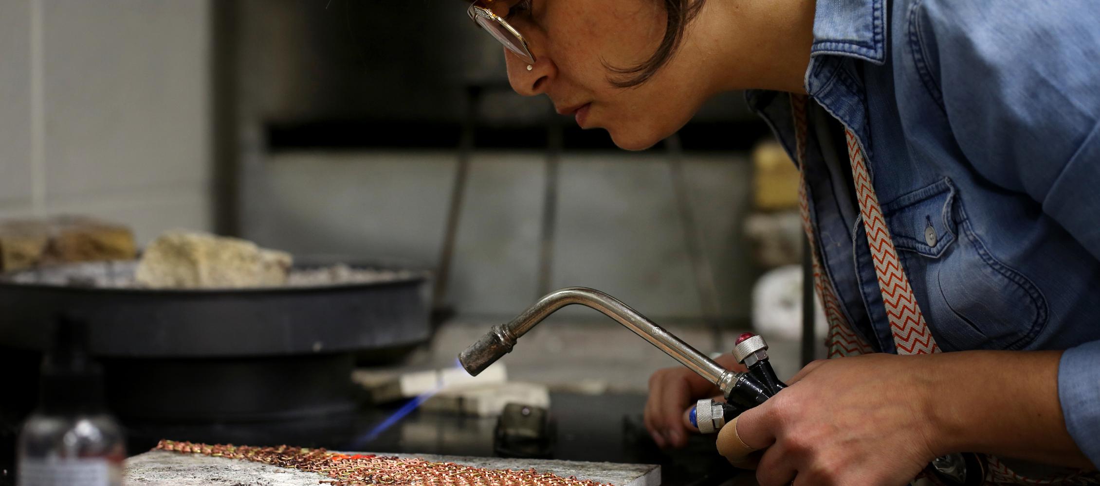 An international student from Israel uses a small torch to solder jewelry.