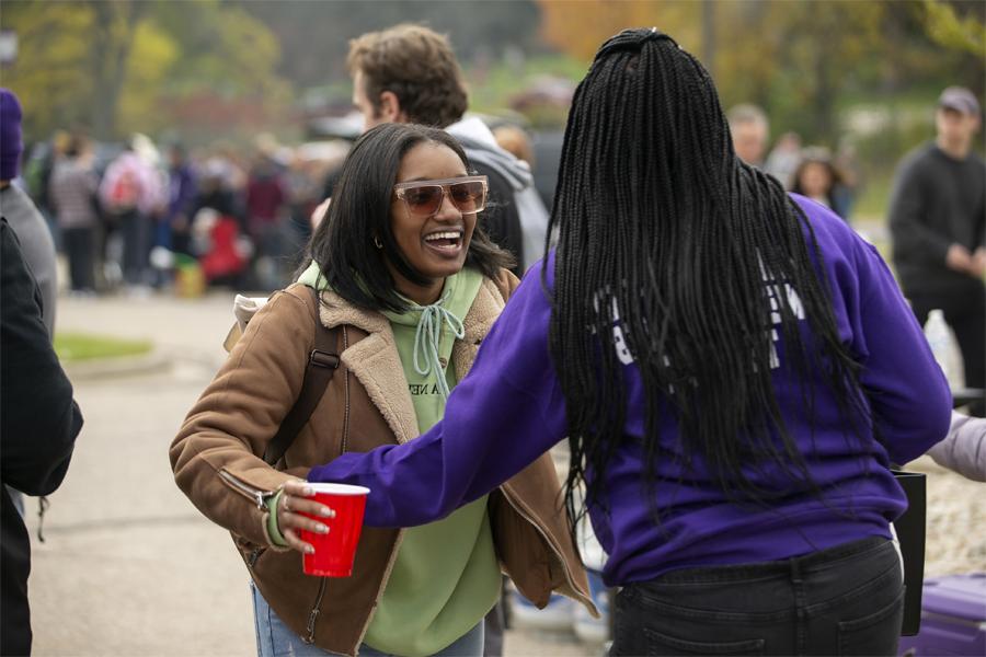 Two people smile and hug outside during a tailgate.