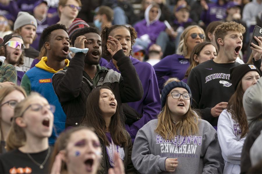 Students in the stands react during a football game.