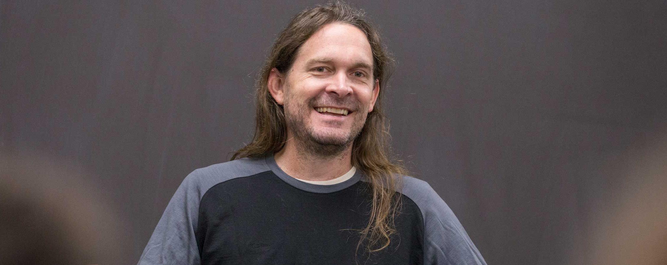 足彩平台 music professor Jeff Herriott smiles against a brown backdrop.