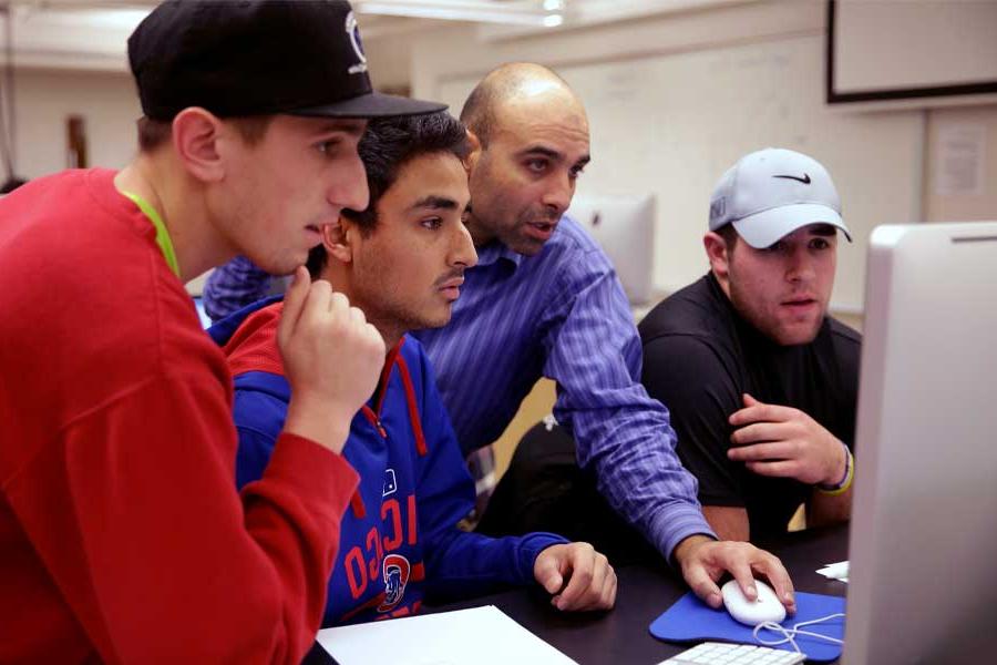 Jalal Nawash works with students on a computer.