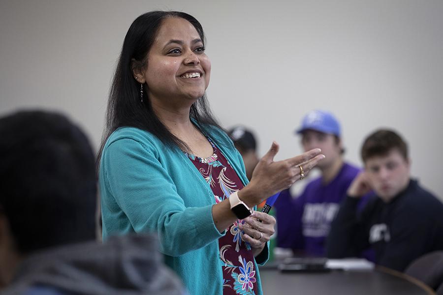 Rashiqa Kamal smiles and stands with her arms extended during a lecture.